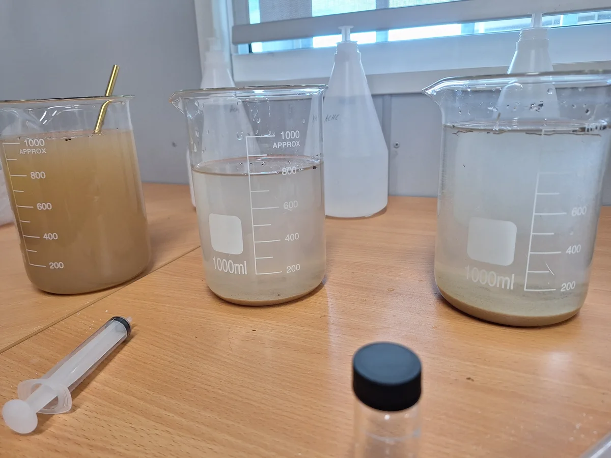 HES Basin jar-test beakers with a cloudy brown sample and clearer samples with settled solids